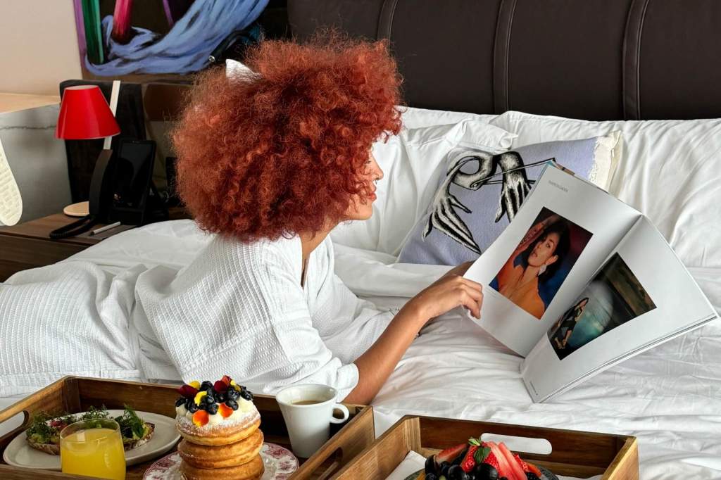 Woman reading a magazine in bed with breakfast on a tray