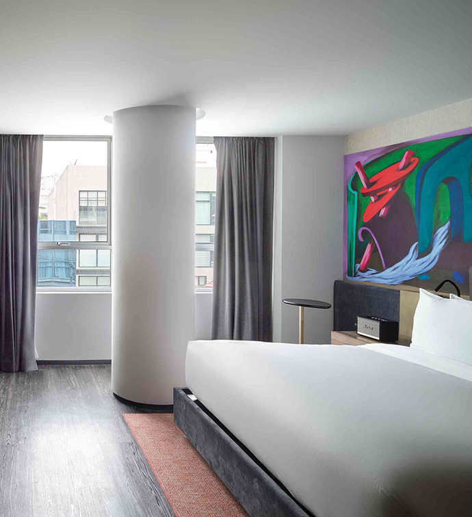 A hotel room featuring a spacious bed and a vibrant painting on the wall.