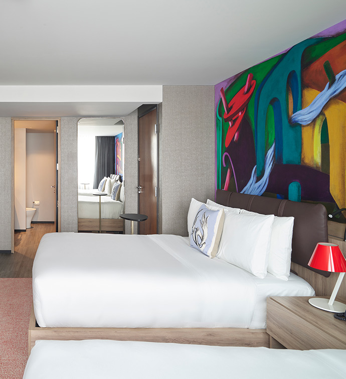 A hotel room with two beds and a vibrant wall decor.