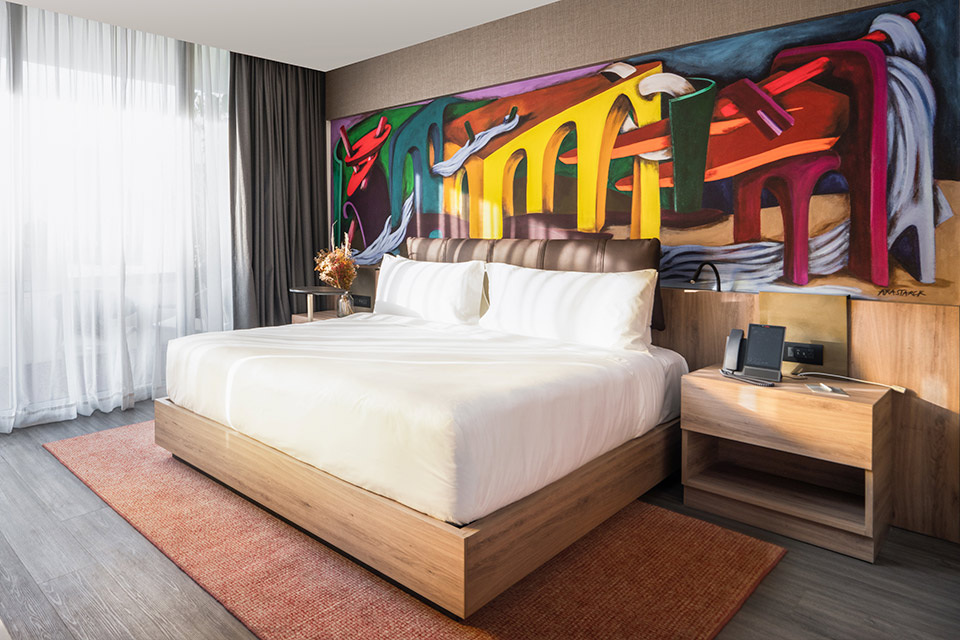 Hotel room at the Mondrian Mexico City Condesa with a bed and giant colorful wall mural