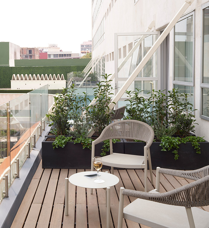 Outdoor balcony with wooden table and chairs overlooking a scenic view.