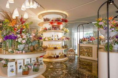 Flower shop with shelves and displays of various flowers in a brightly lit space