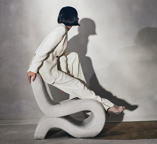 Woman in a white suit sitting on a sculptural chair