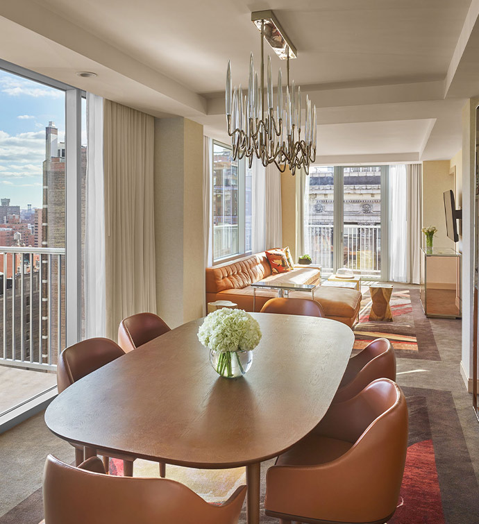 A modern living area with a table and chairs, overlooking the city skyline.