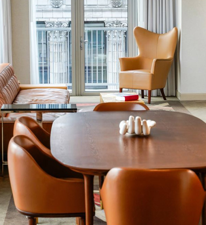 A living space with a brown table, couch and chair in the room with a balcony.