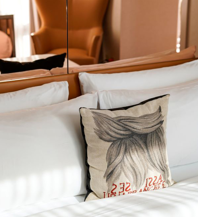 A pillow with a woman's hair drawing on it placed on a bed.