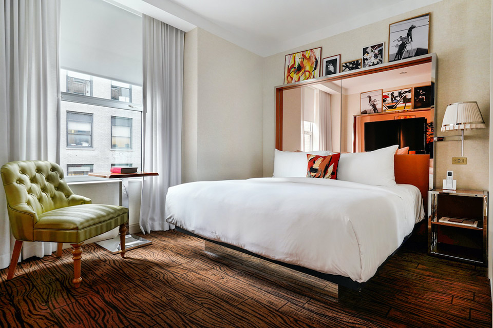 A cozy hotel room featuring a comfortable bed, a chair, and a window offering a scenic view.