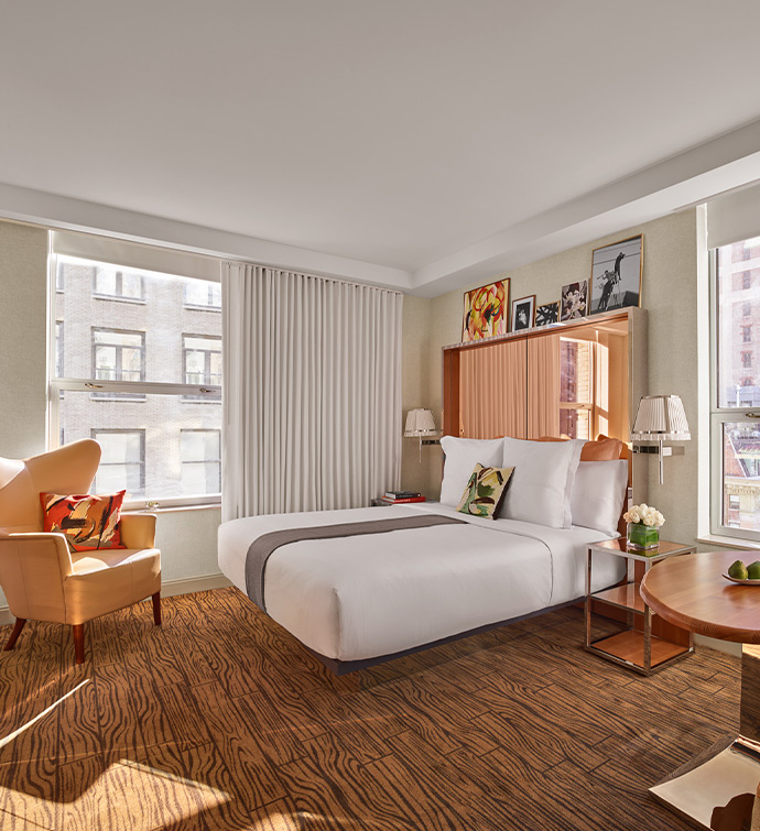 A cozy hotel room with a neatly made bed, a comfortable chair, and a sleek desk.