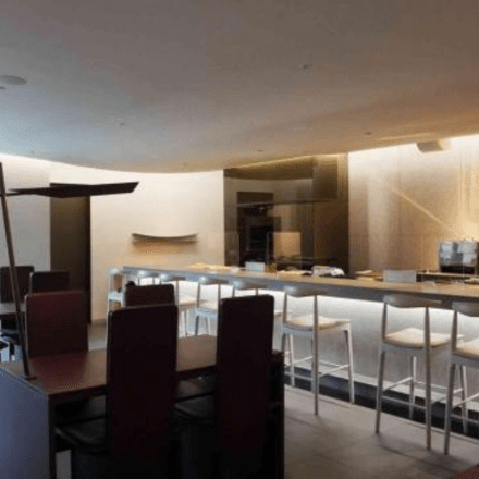 a bar seating area with the bar underlit and tall white barstools