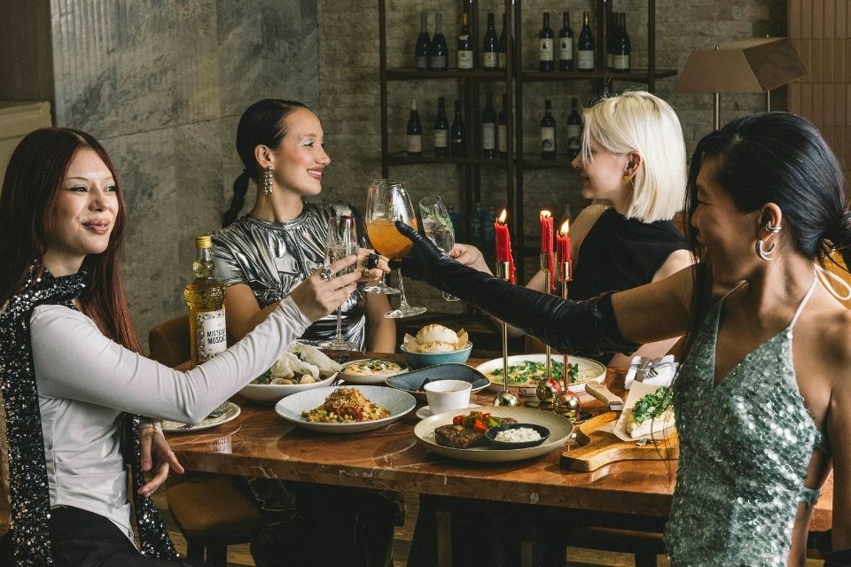 Four friends sitting at a holiday themed table toasting with glasses