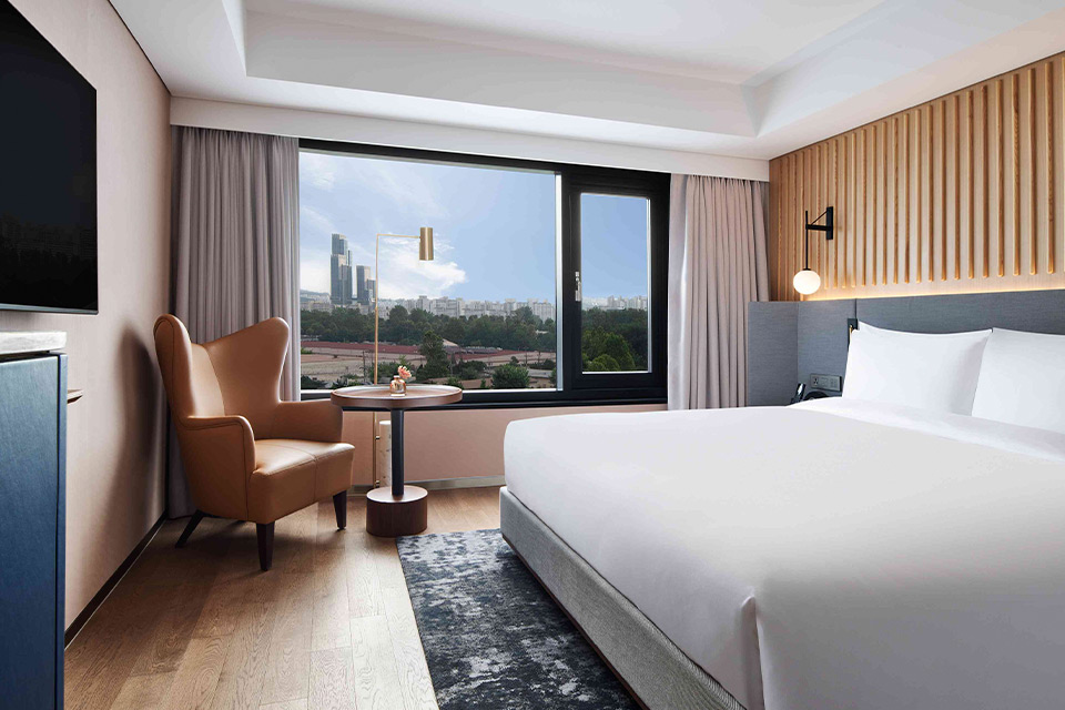 A cozy hotel room featuring a comfortable bed, chair, and television.