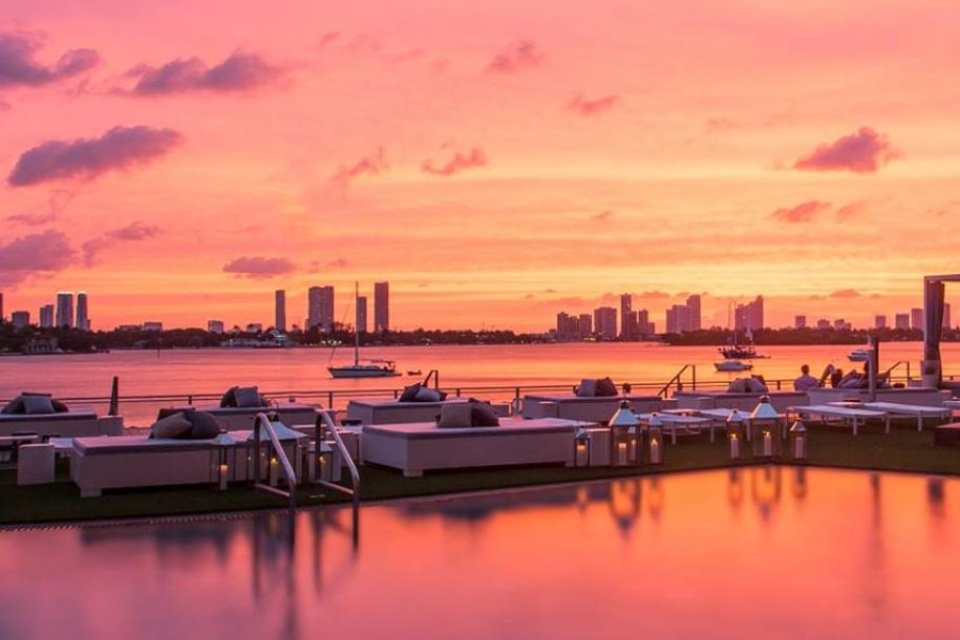 Sunset photo of Baia Beach Club pool and daybeds overlooking the water