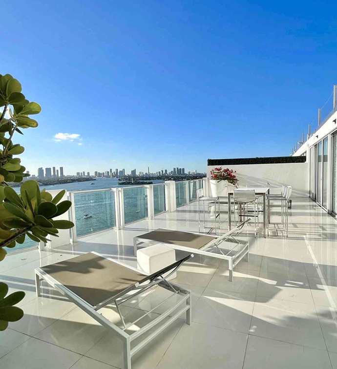 A balcony overlooking the ocean, featuring white furniture and a serene view of the sea.