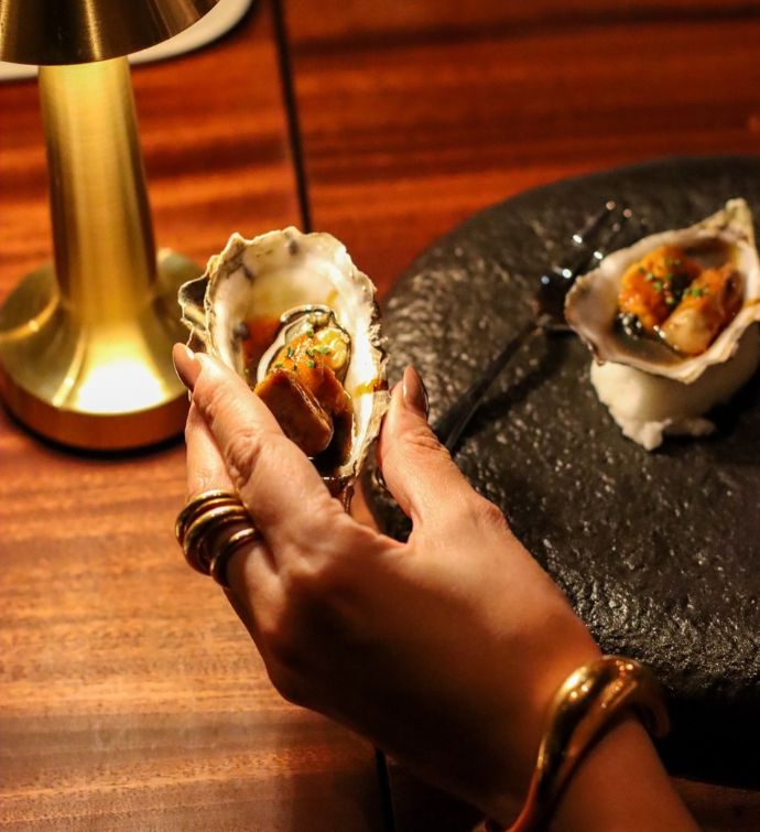 Hand holding fresh oysters at Morimoto Bordeaux