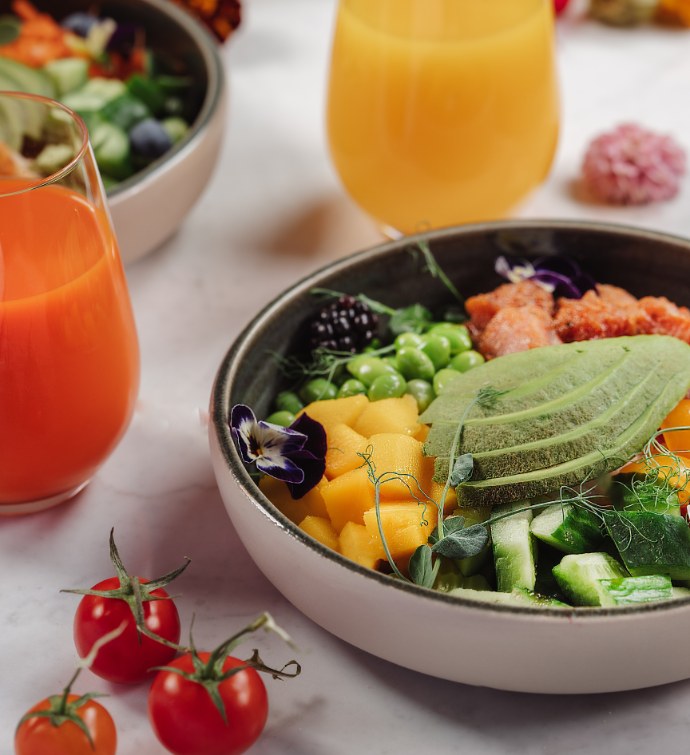 Bowl with avocado, blackberries, cucumbers accompanied by fresh juices