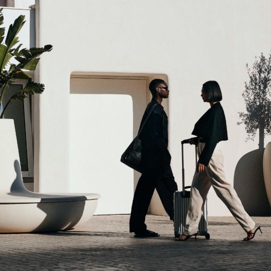 Two people walking with luggage in front of Mondrian Ibiza