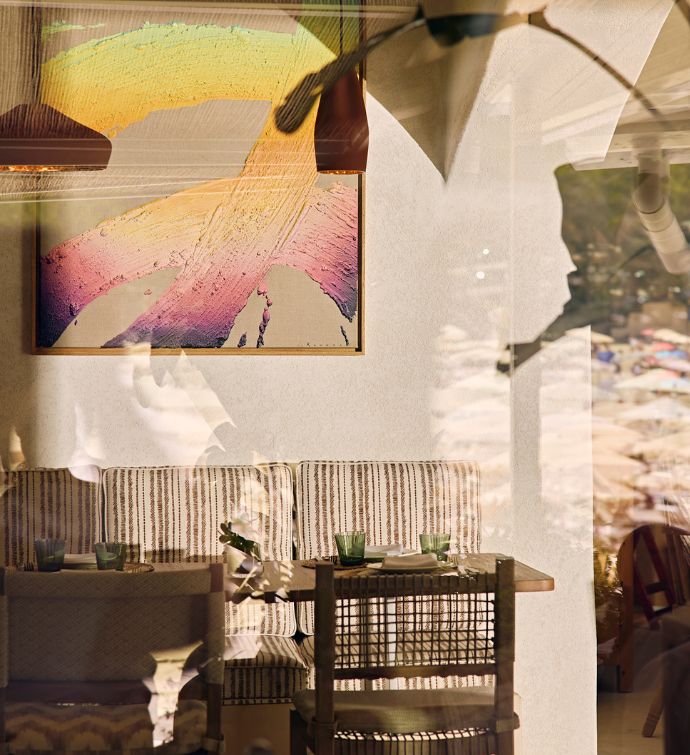 Dining room with striped booths, wicker chairs, colorful art work on the walls, and hanging light