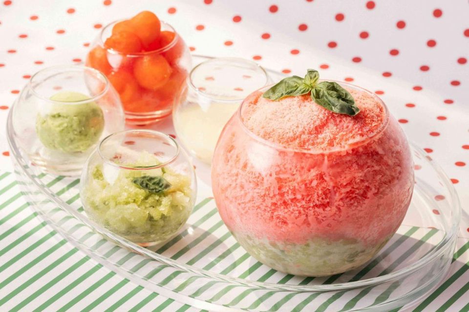 Large bowl of bingsoo with toppings in other smaller bowls on a striped and polka dot surface