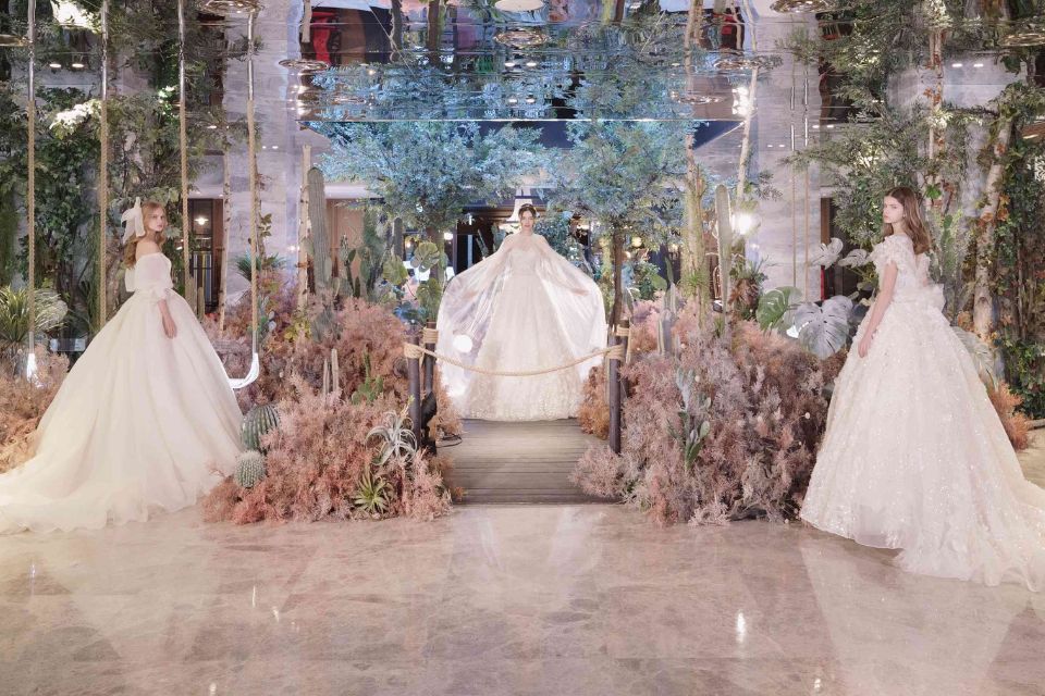 Three brides in wedding dresses pose in an entrance filled with flowers