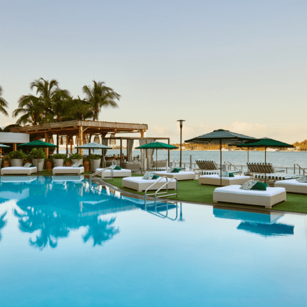 a beautiful pool with luxurious lounge chairs and umbrellas surrounding it. Overlooking the bay