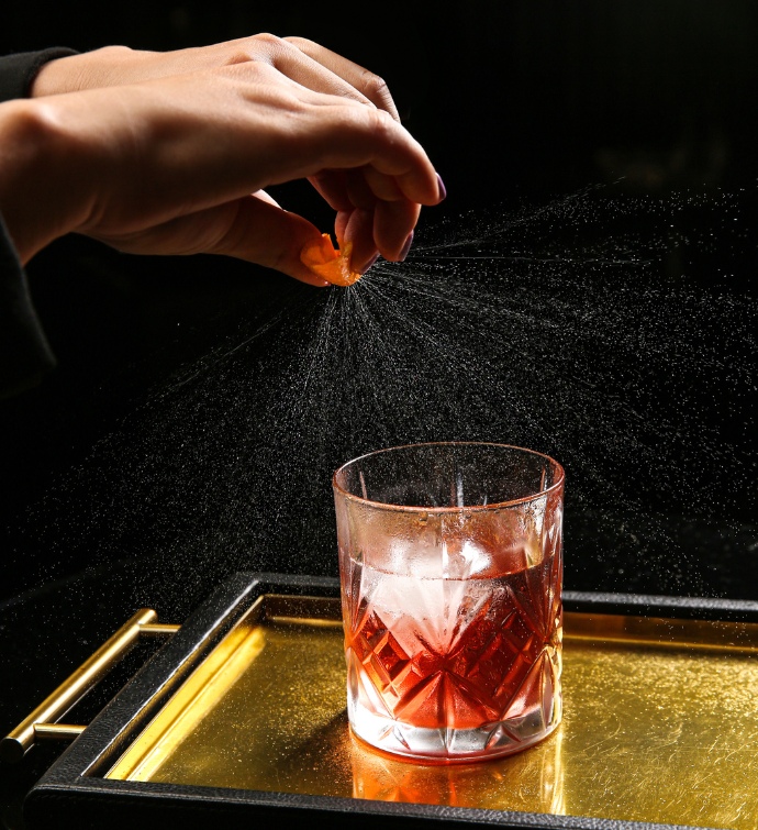 Hand putting a spritz on a red cocktail 