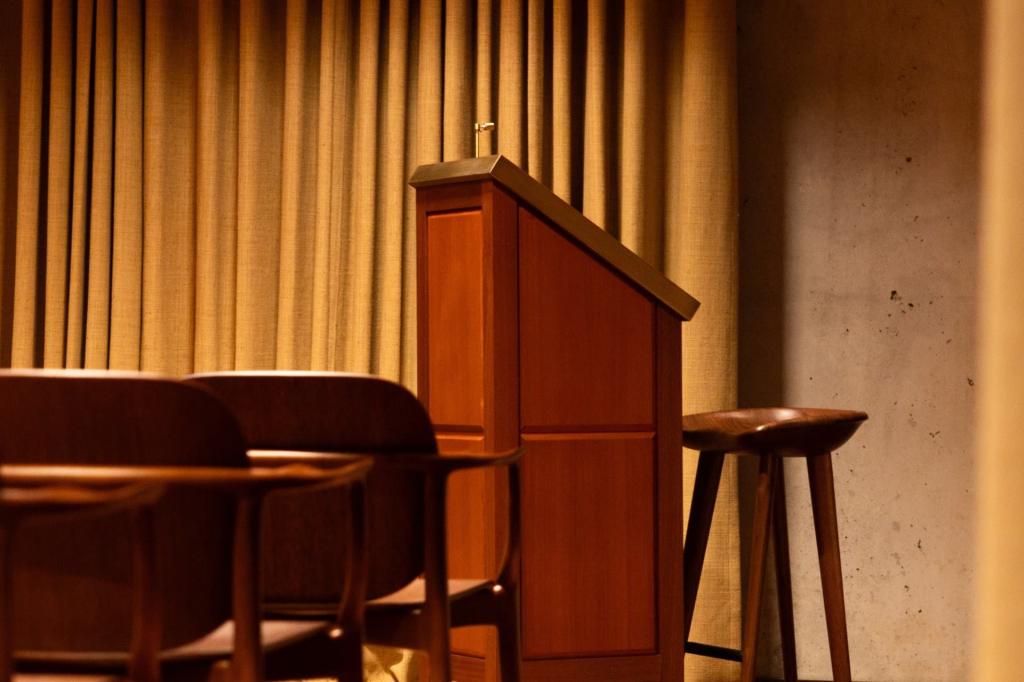 Podium with a stool behind it, facing seating