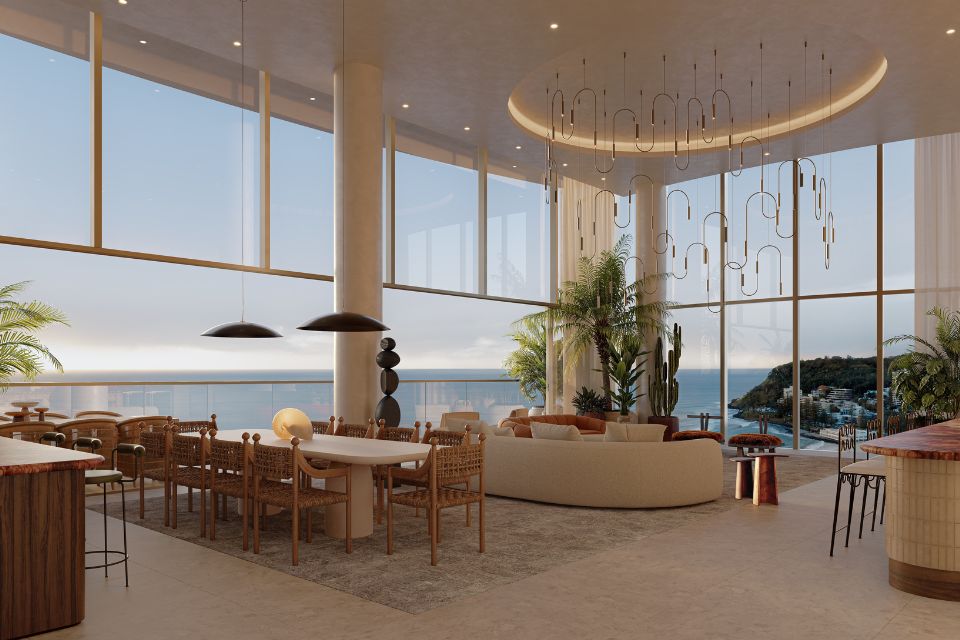 Sprawling hotel corner suite with windows overlooking the sea, a large dining table, and a large cream sofa