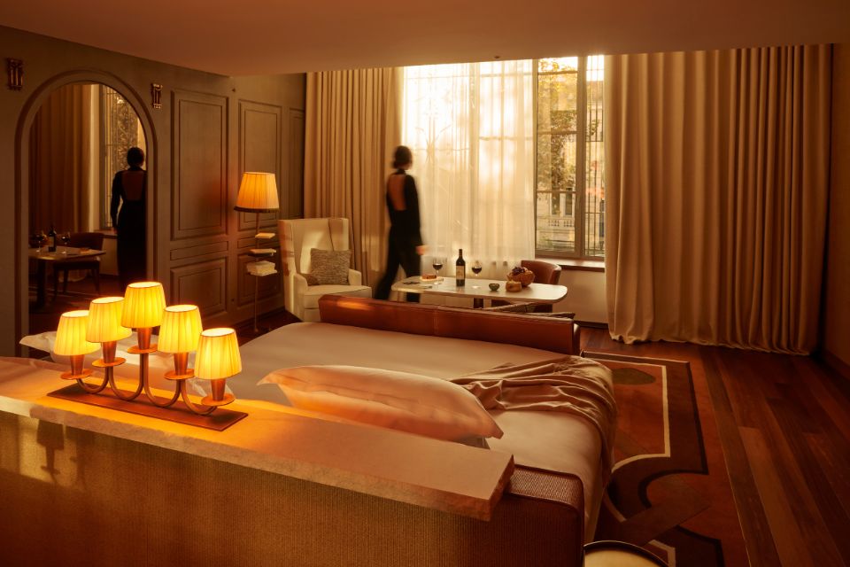 Person in a large dimly-lit hotel suite looking out of floor-to-ceiling windows