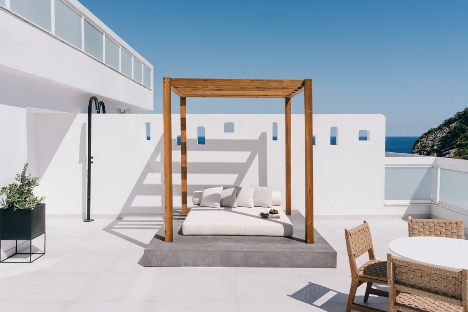 Private terrace with white walls, white daybed, and light wooden canopy structure