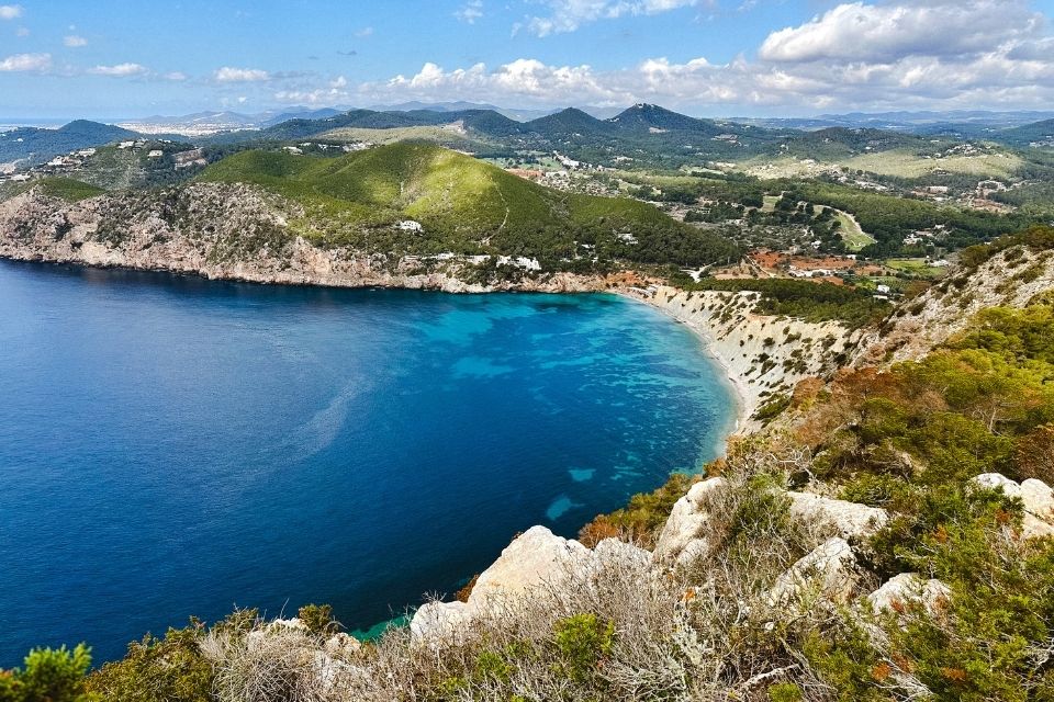 Large blue sea with mountains in the background and blue skies with clouds