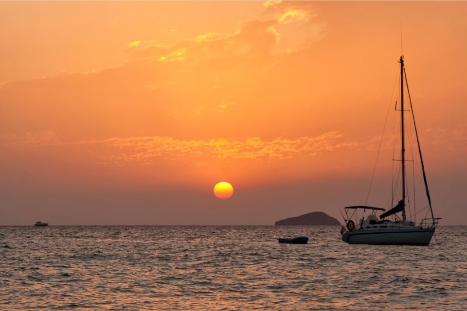 Small sailboat with the sun setting on the ocean