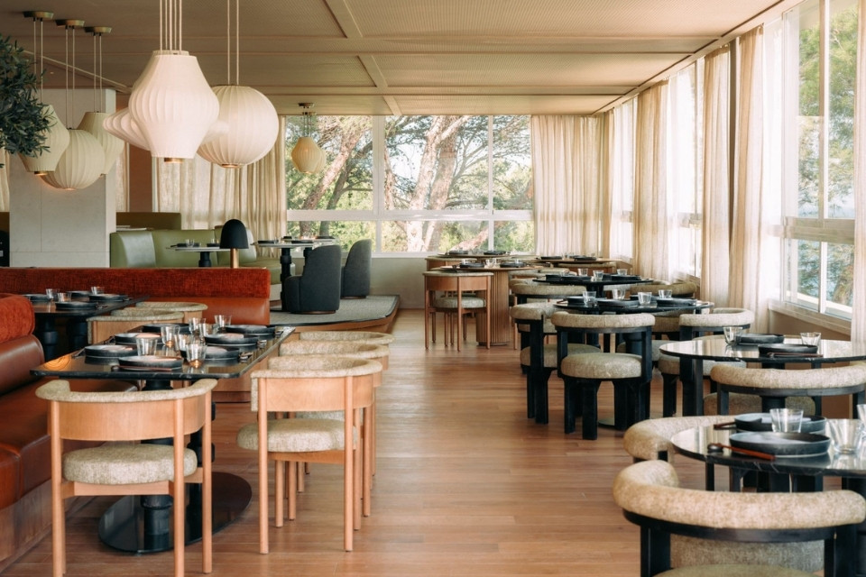 Large dining room with mixed modern seating and dining tables and white hanging chandeliers