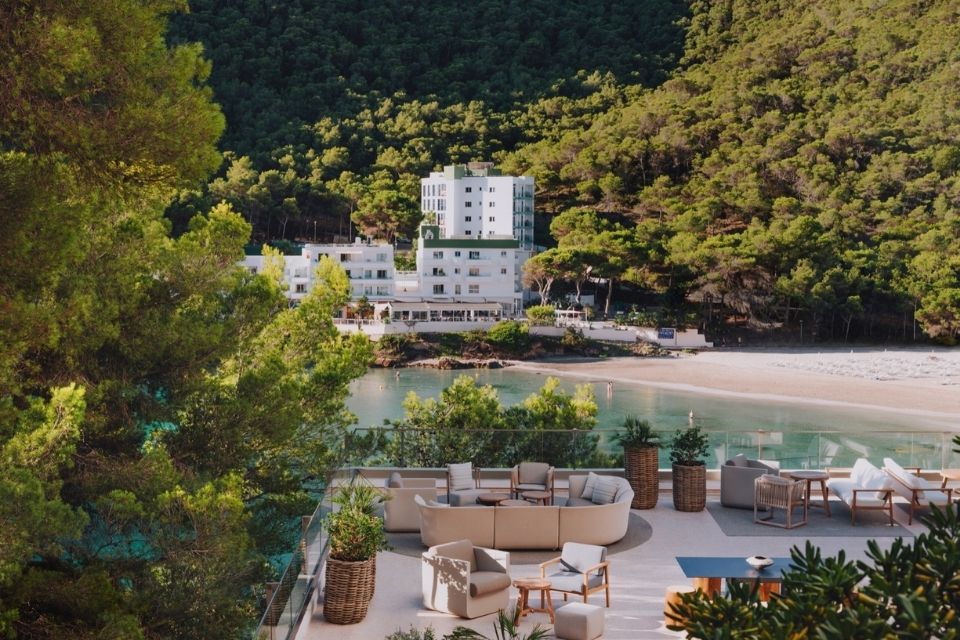 Aerial view of large patio with outdoor furniture looking over a beach with a white building in the background