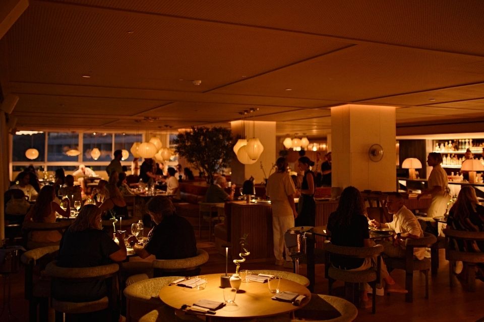 Warmly lit restaurant dining room at night filled with people sitting at tables