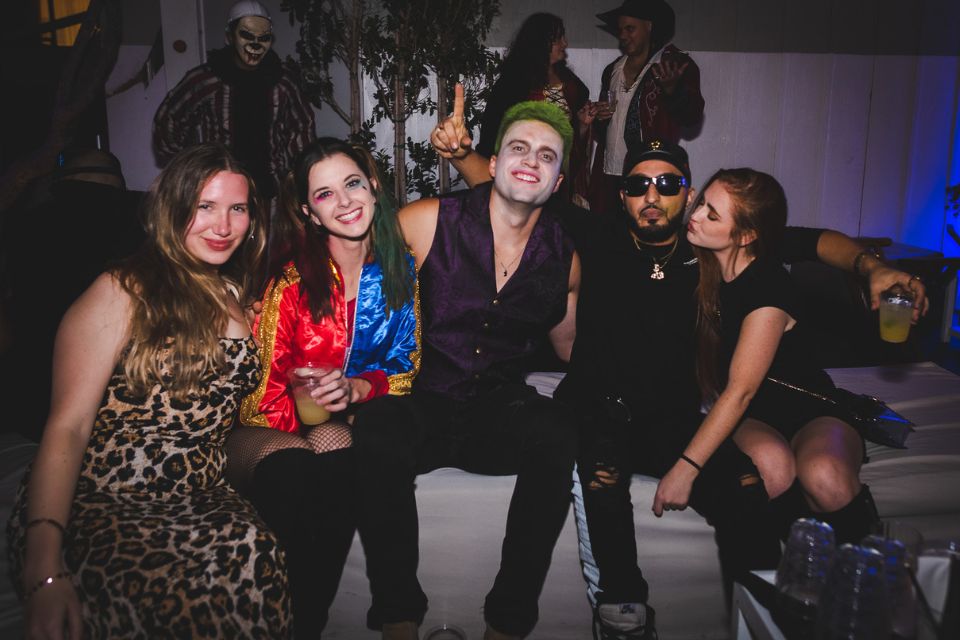 Group of people in halloween costumes pose in a nightclub setting