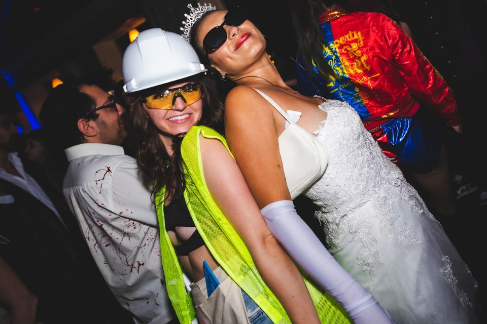 Two women, one in construction worker costume and one in princess costume, pose for a photo