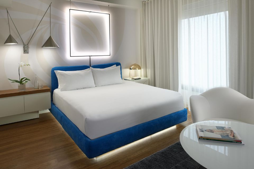 Large white bed with turqouise headboard in a sleek white hotel room