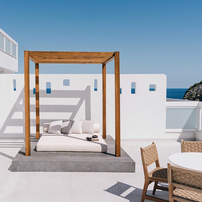 White patio with wooden daybed and table.