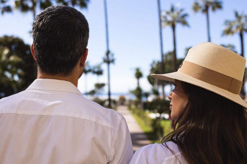 Back of man and woman looking out to blue sky and palm trees