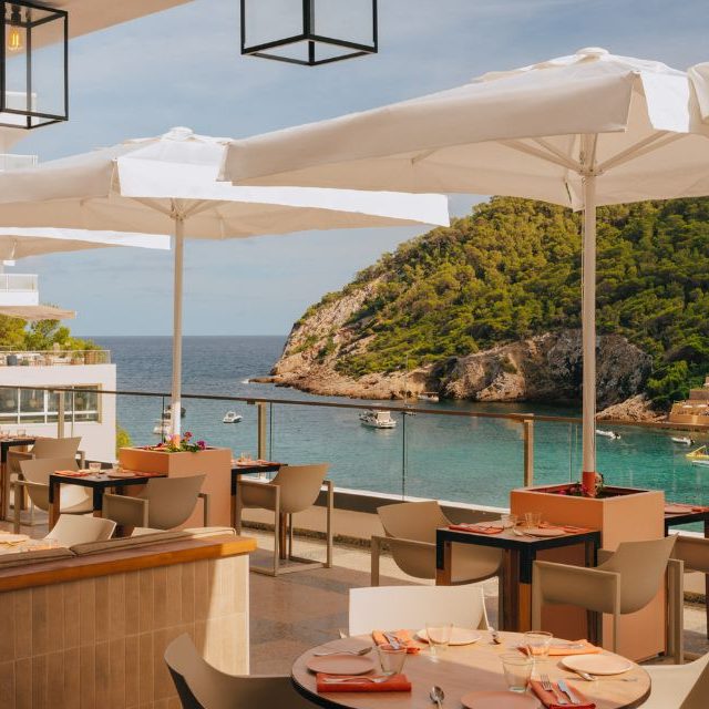 Patio with umbrellas, tables, and ocean in the background