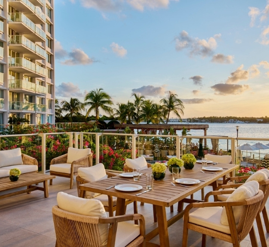 Outdoor terrace with rectangular wooden table overlooking the ocean and sunset sky